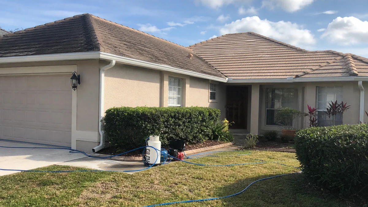 Low-pressure soft wash treatment being applied to a roof slope